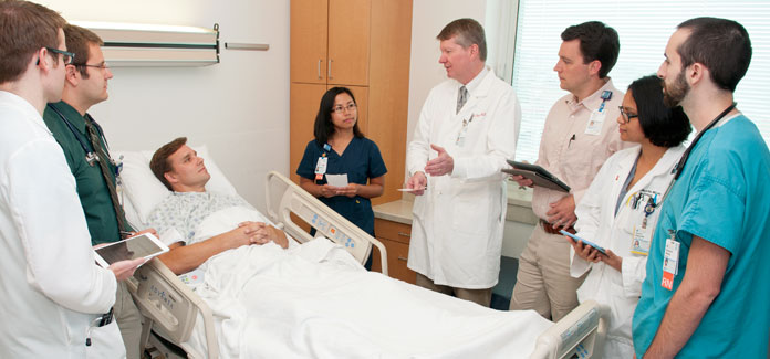 DOM Cardiovascular faculty member John Dent, MD (center) talks to patient care team members about the importance of structured interdisciplinary bedside rounding in achieving clinical excellence.